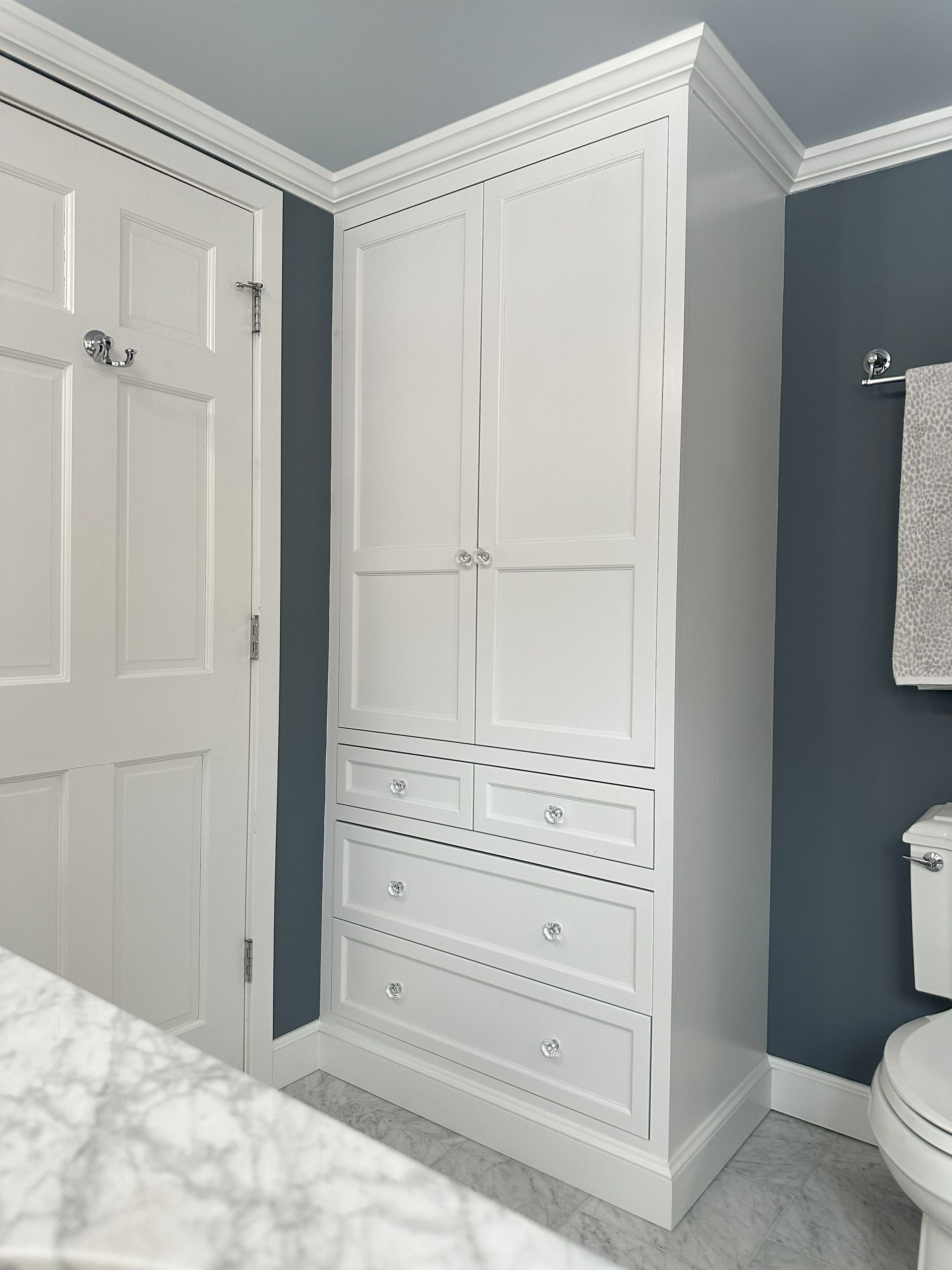 A bathroom with a white cabinet and a toilet