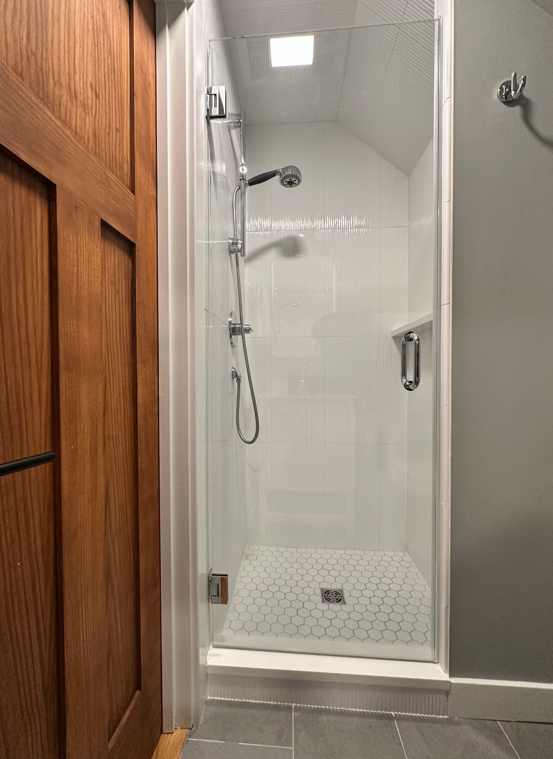 A bathroom with a walk in shower and a wooden door.
