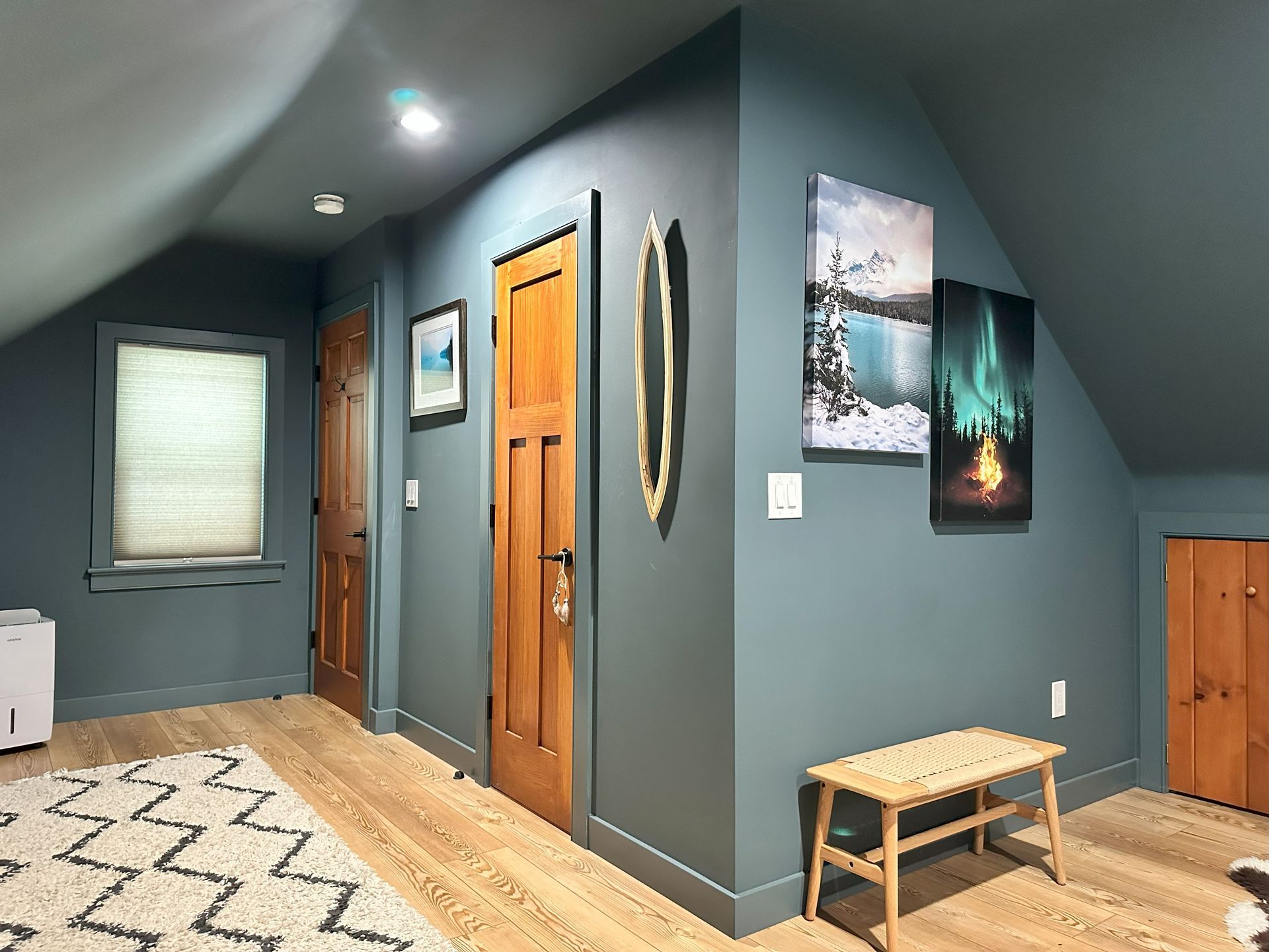 A hallway in a house with a bench and paintings on the wall.