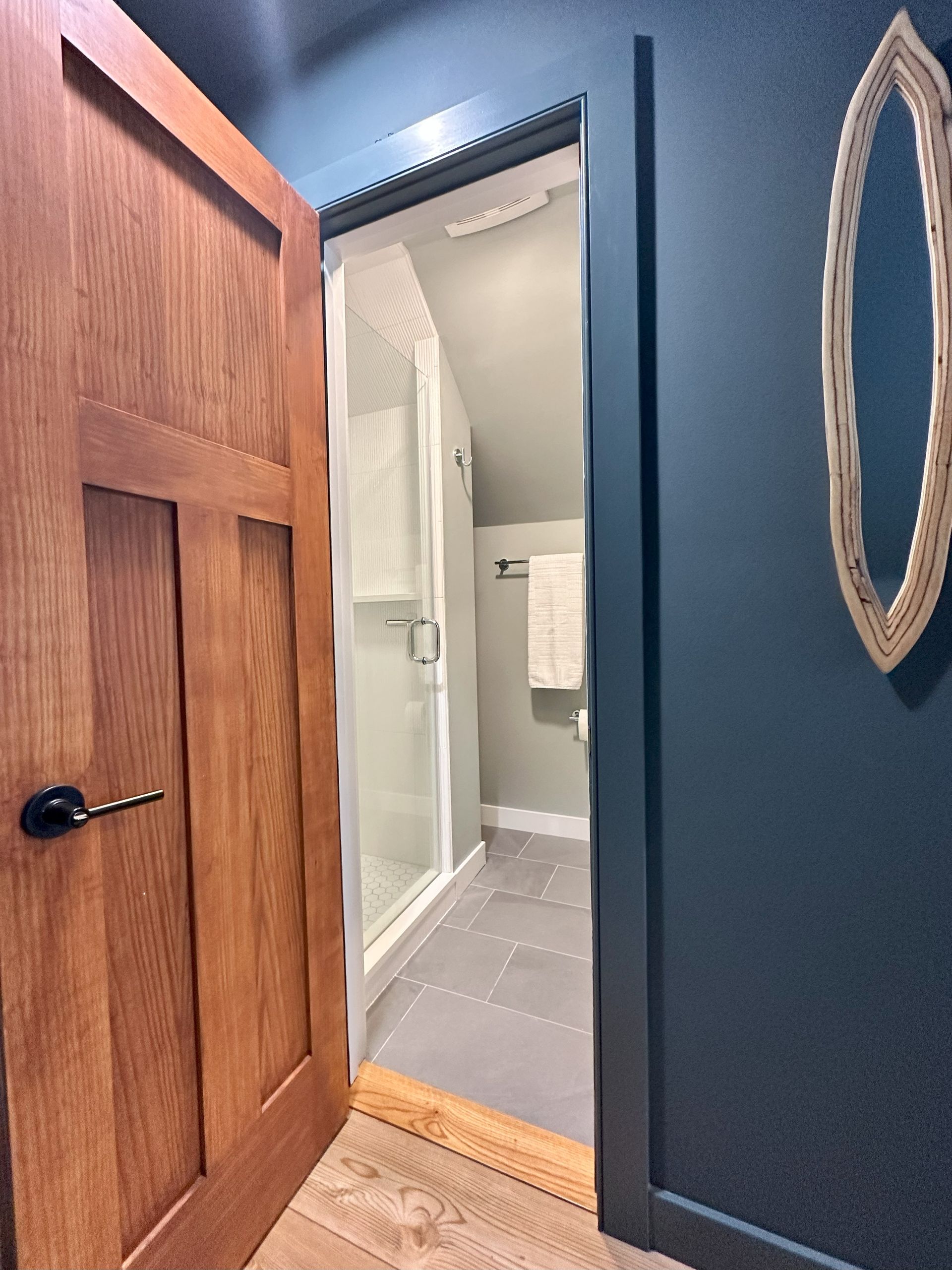 A bathroom with a wooden door and a mirror on the wall.
