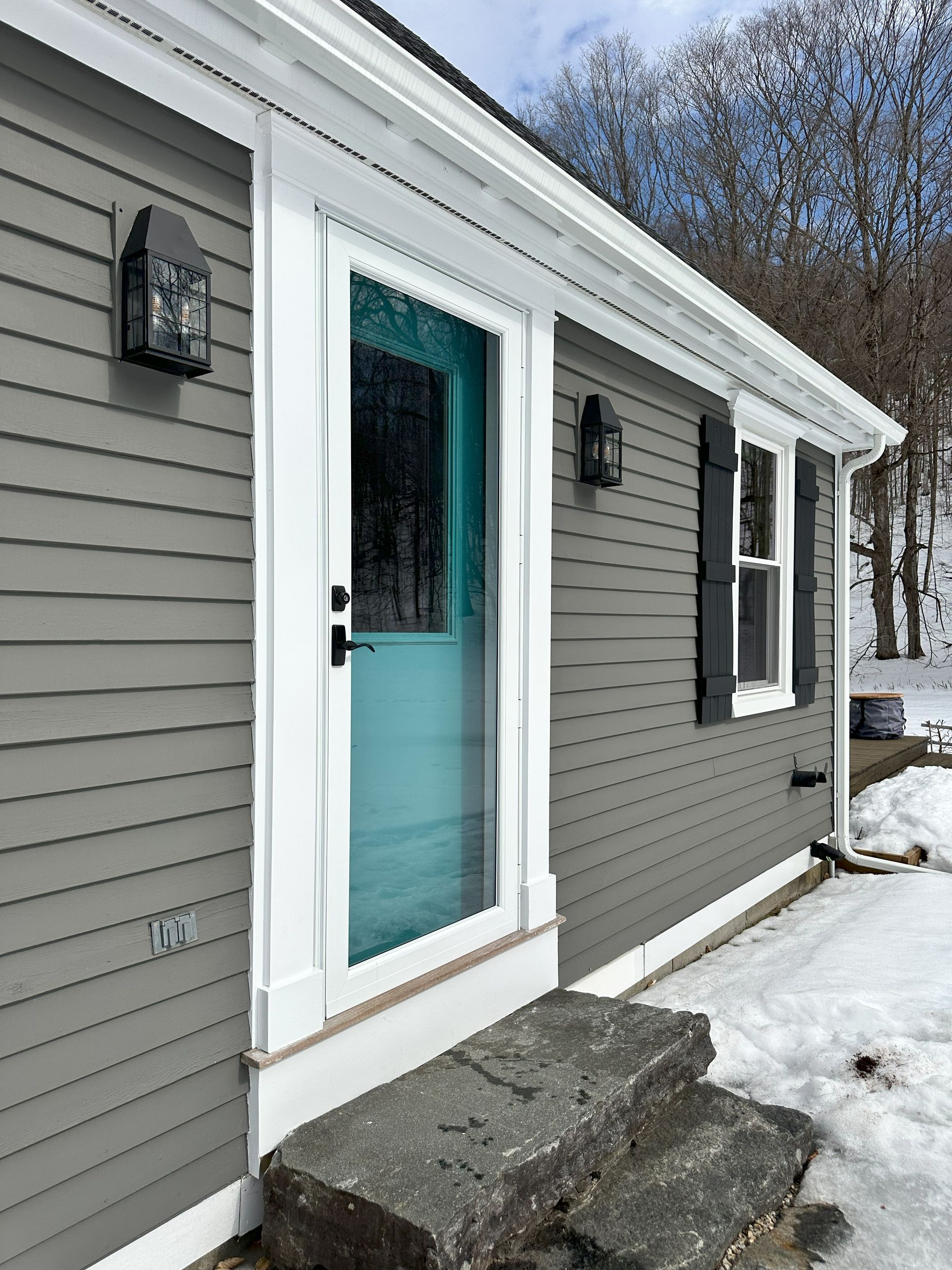 A house with a blue door and steps in the snow.