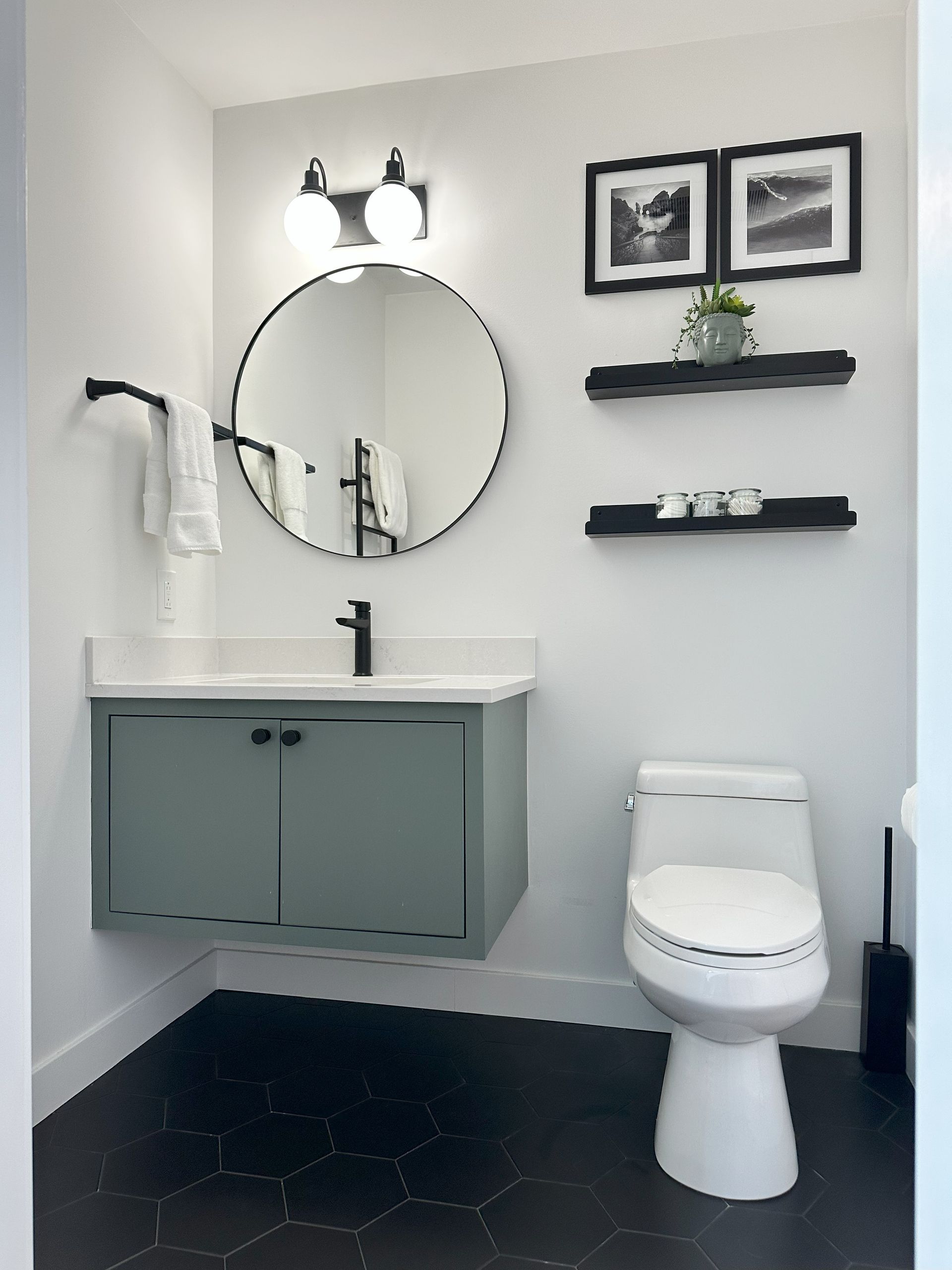 A bathroom with a toilet , sink , mirror and shelves.