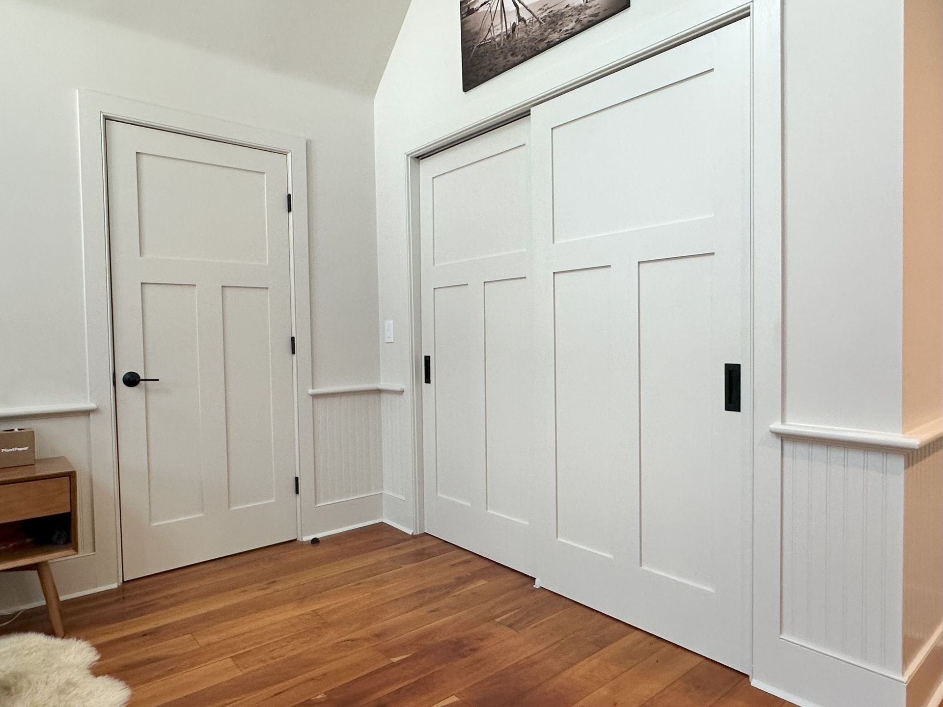 A room with hardwood floors , white walls and sliding doors.