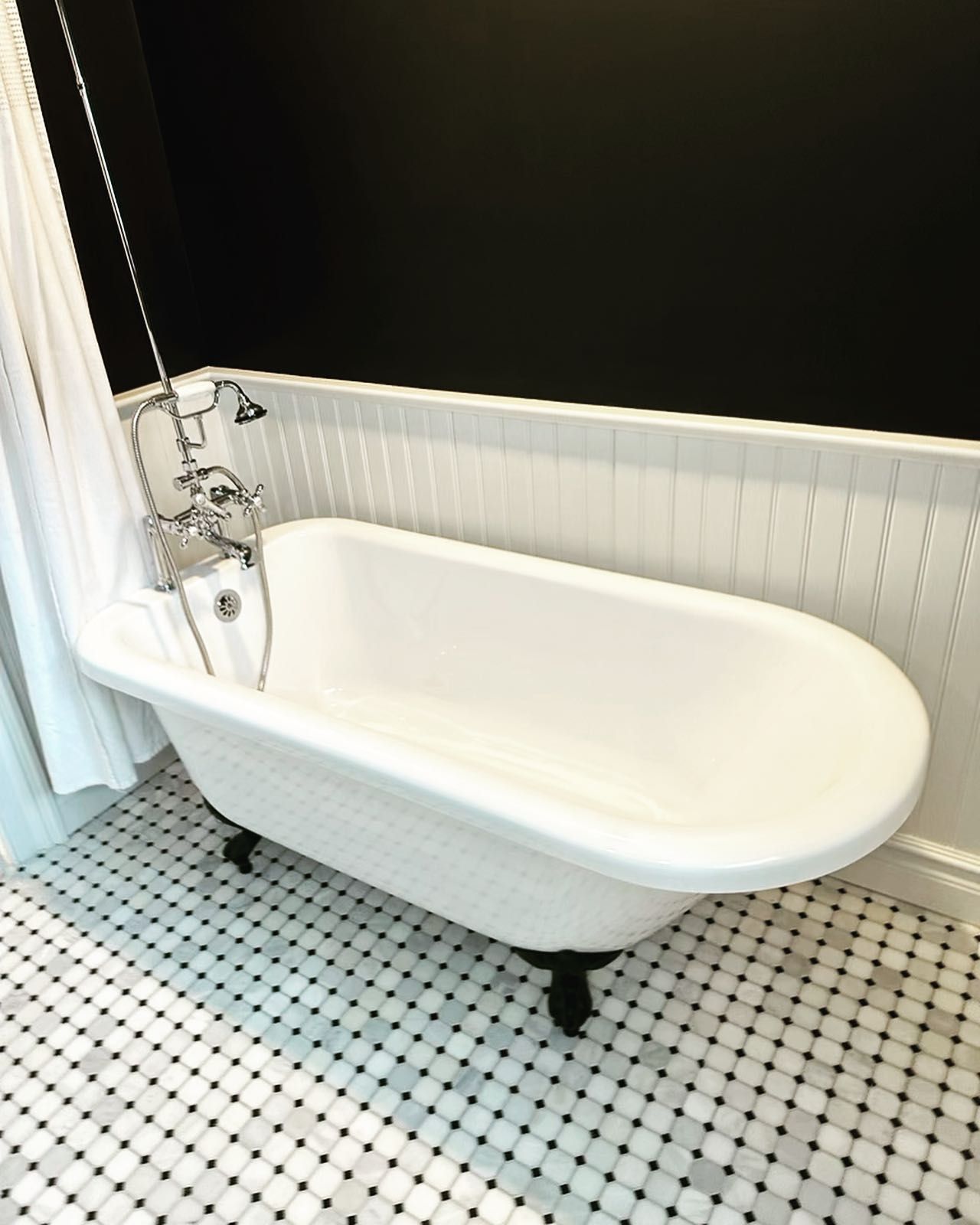 A white bathtub is sitting in a bathroom next to a shower curtain.