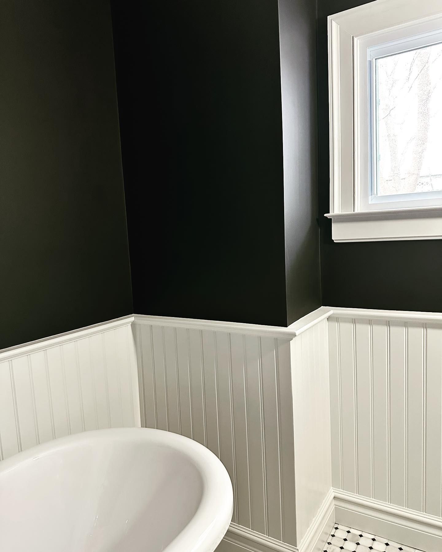 A bathroom with black walls and white trim and a window