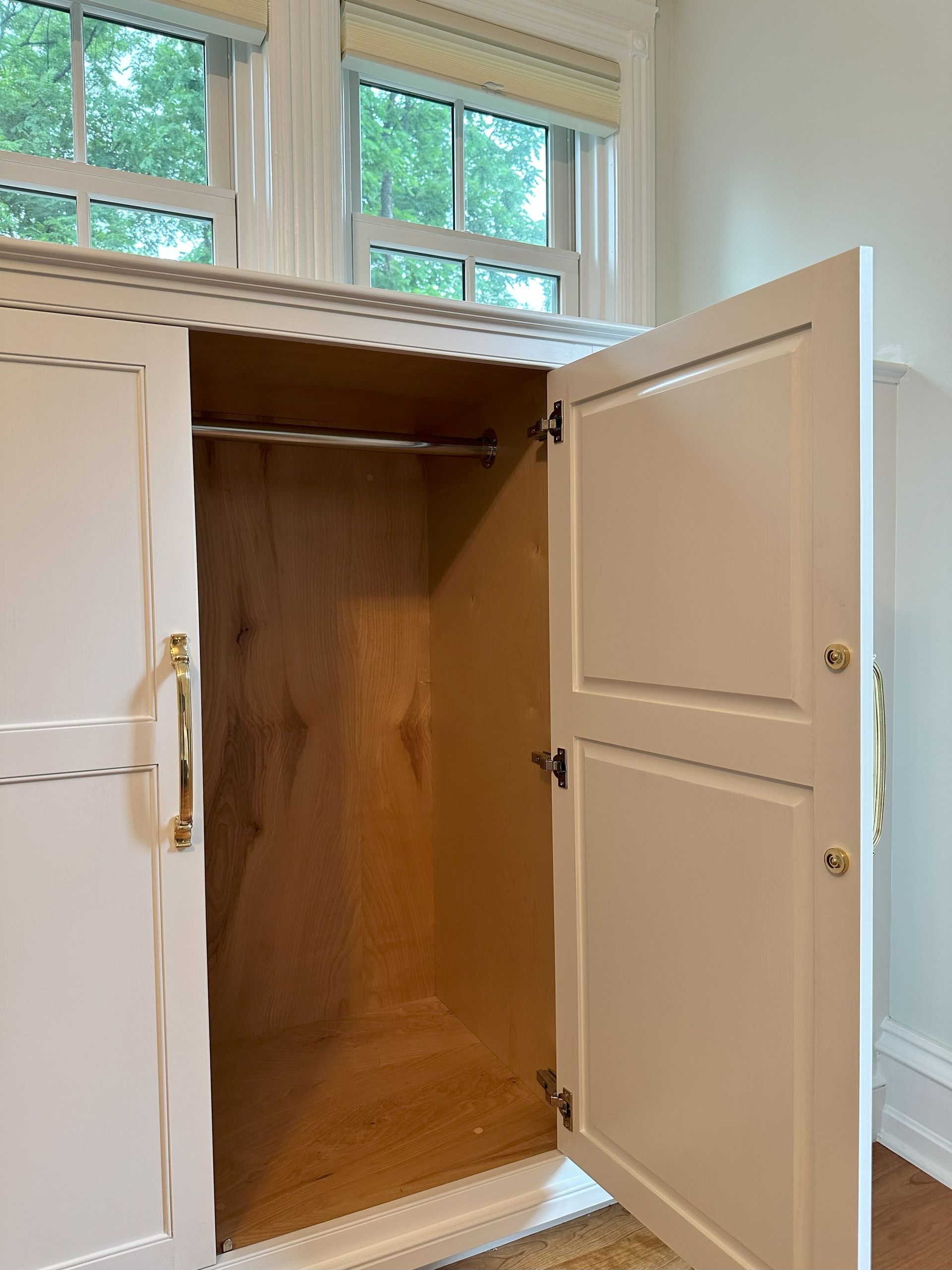 A white cabinet with the door open and a window in the background
