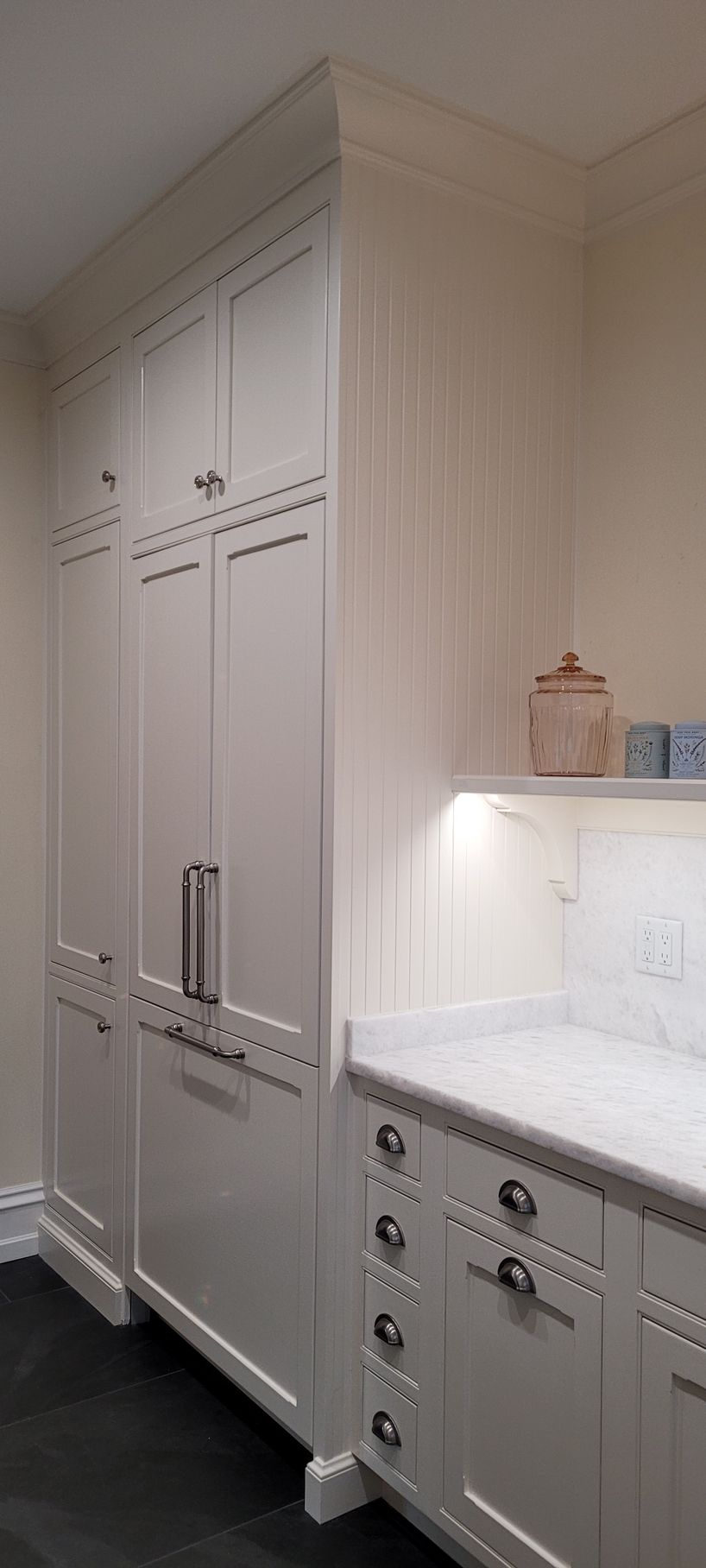 A kitchen with white cabinets and a marble counter top.