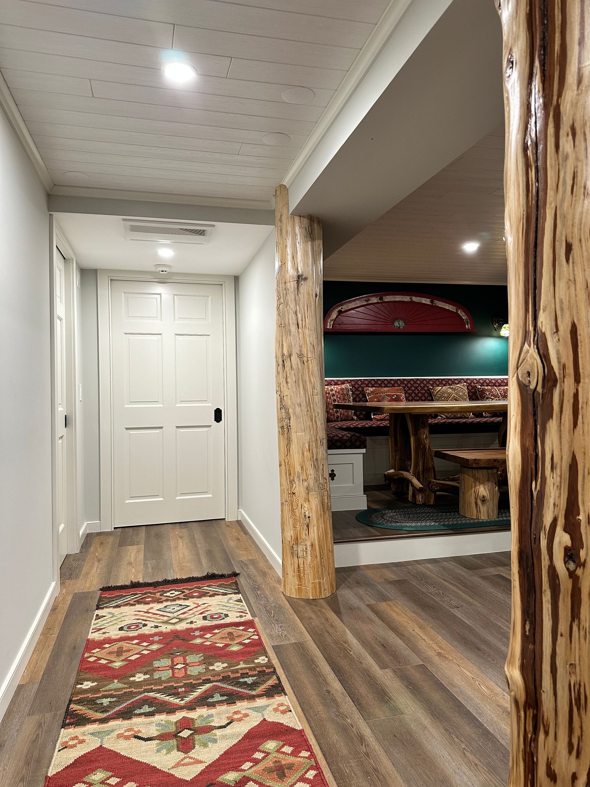 A hallway with a rug on the floor and a wooden post in the middle.