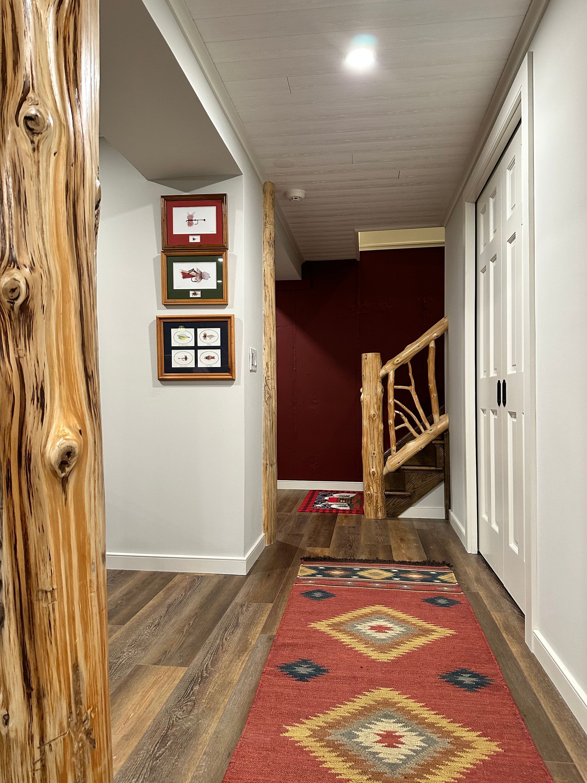 A hallway with a red rug and a wooden staircase.