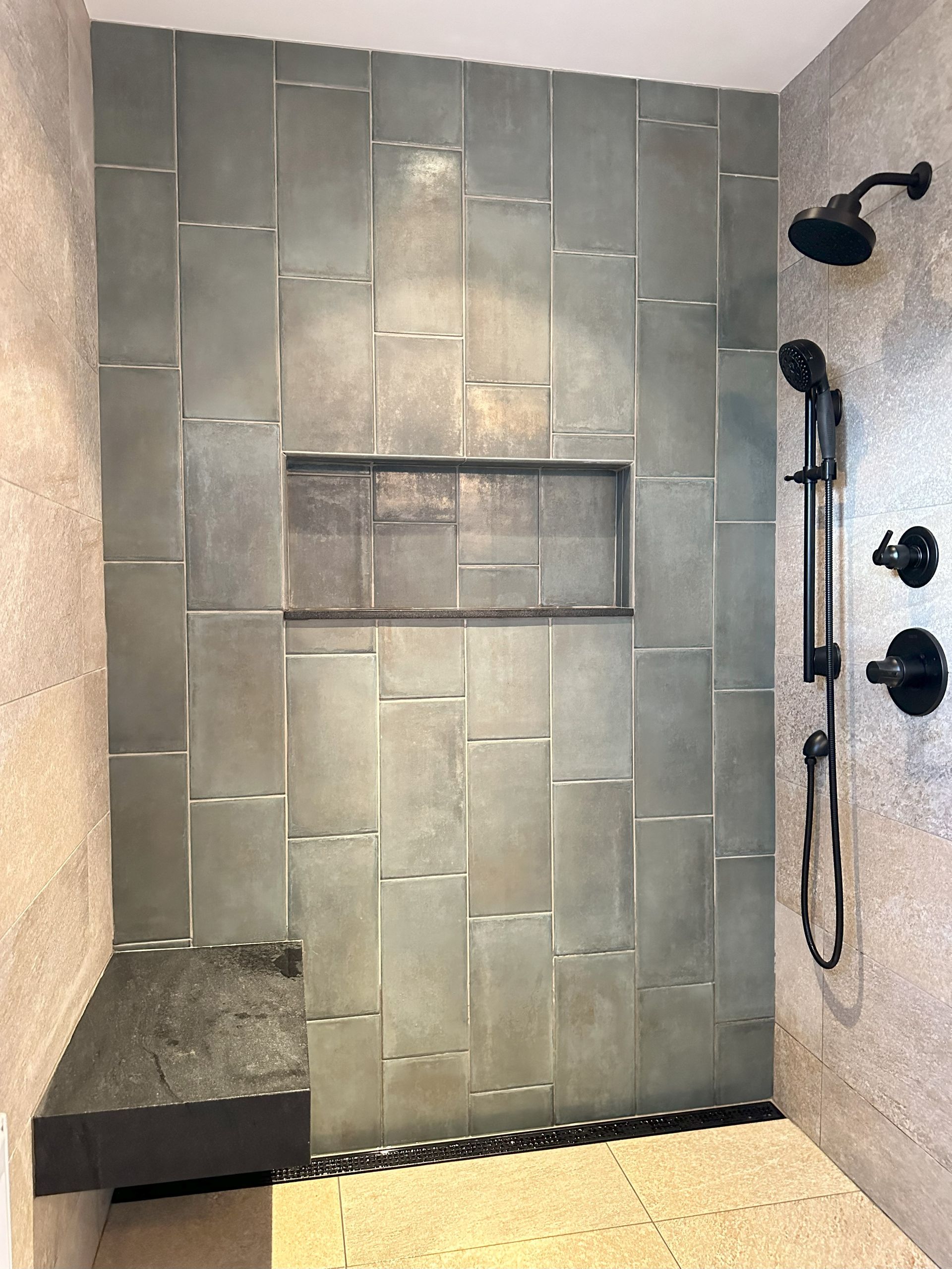 A bathroom with a walk in shower and a bench.