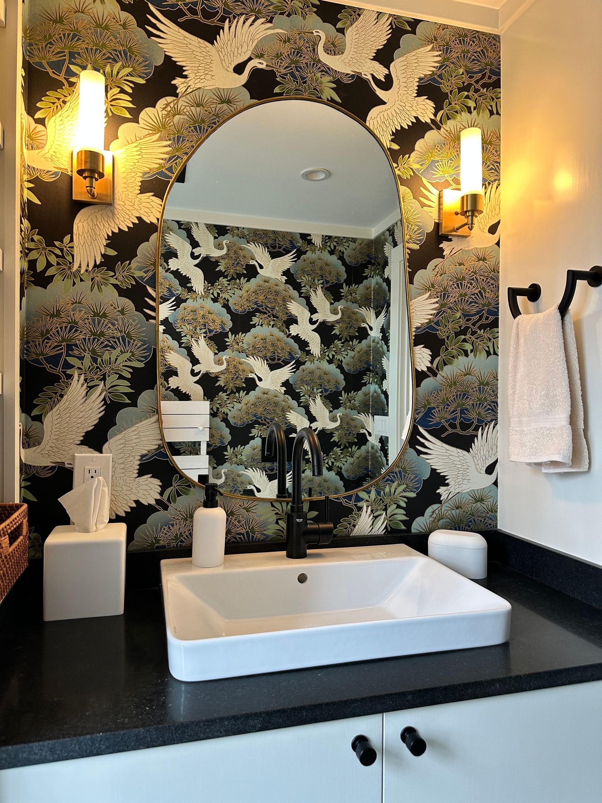 A bathroom with a sink and a mirror with birds on the wall