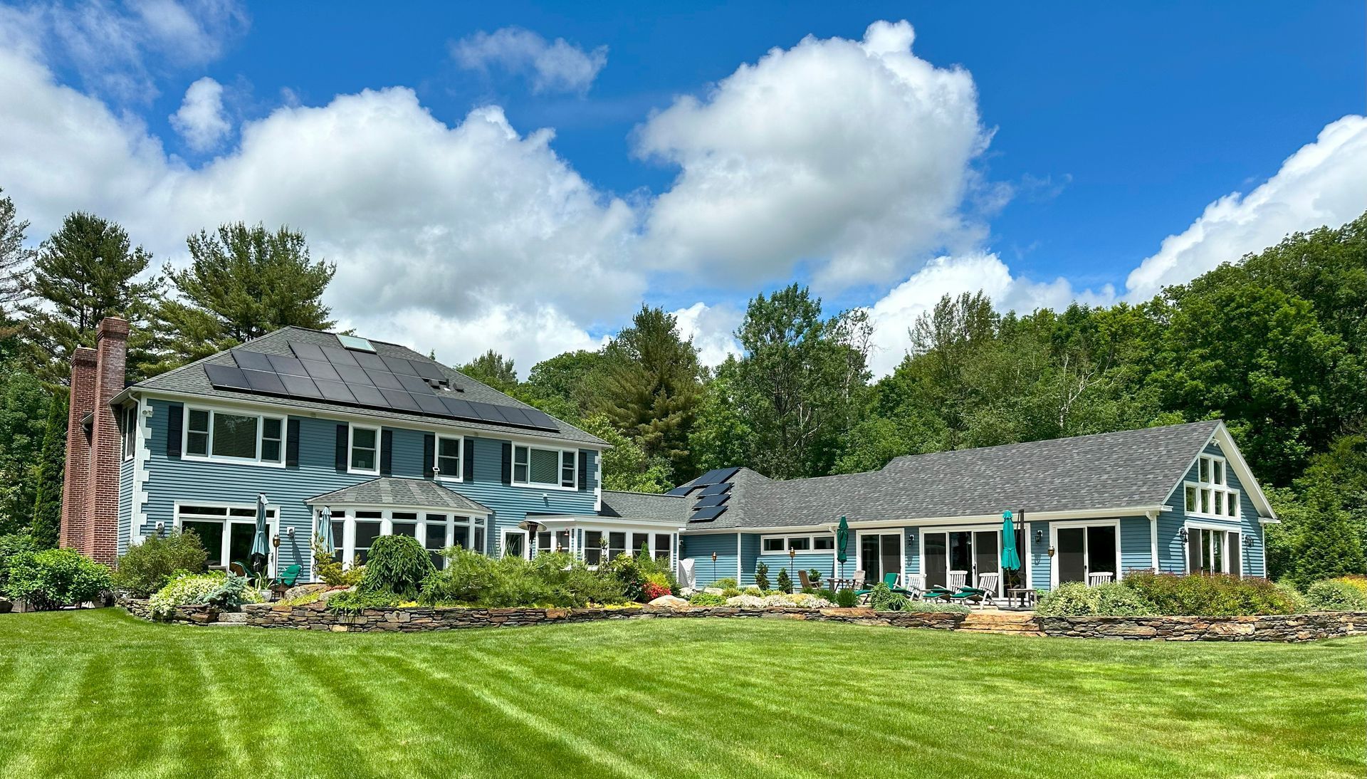A large blue house is sitting on top of a lush green field.