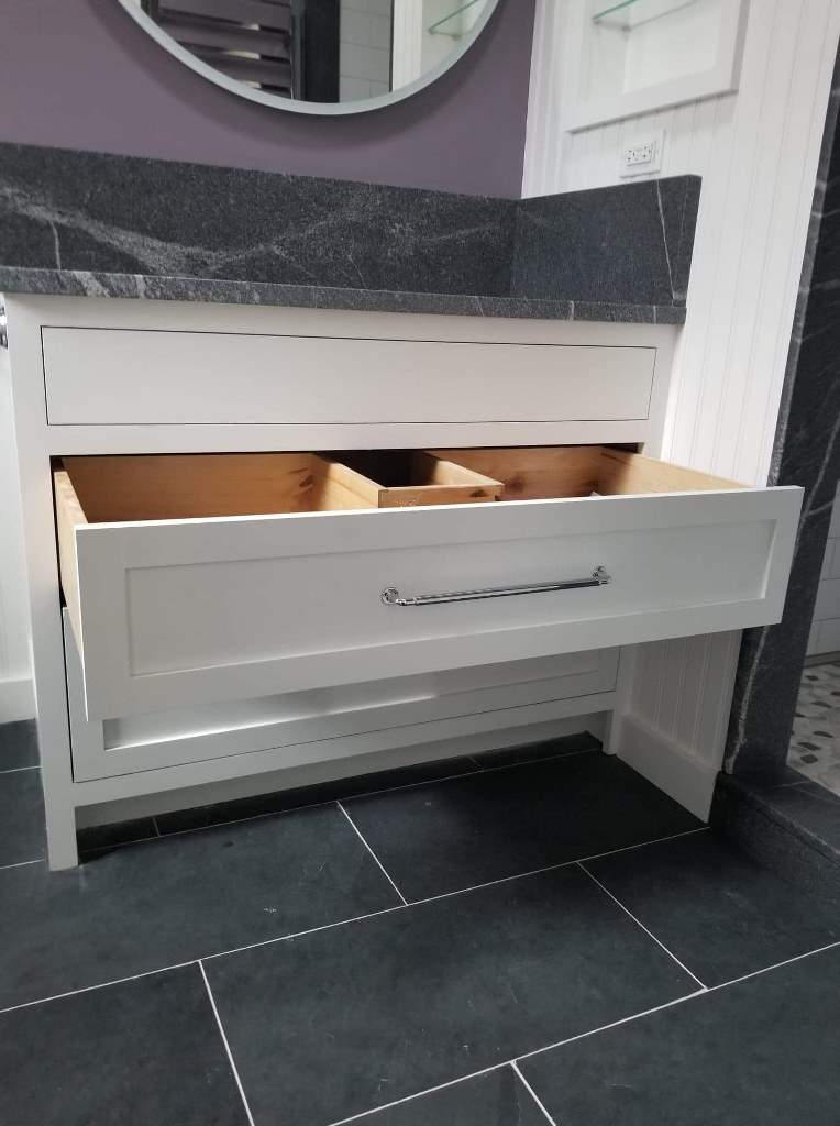 A bathroom vanity with drawers open and a mirror.