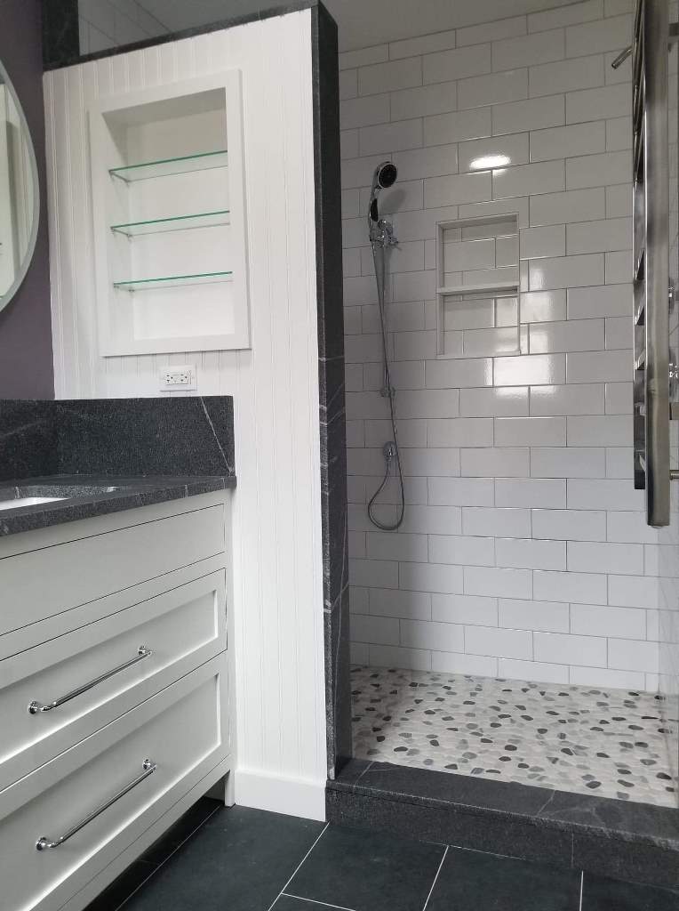A bathroom with a walk in shower and a sink