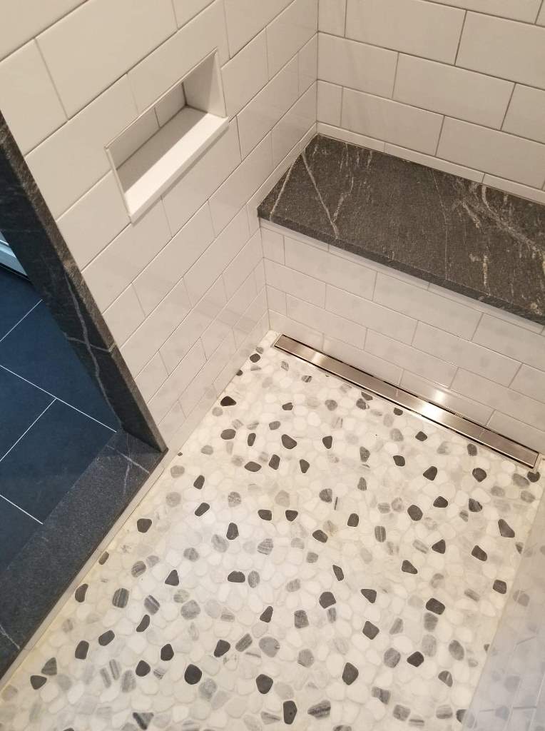 A bathroom with a walk in shower and a bench.