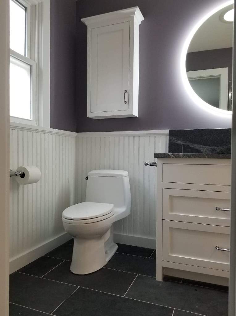 A bathroom with a toilet , sink and mirror.