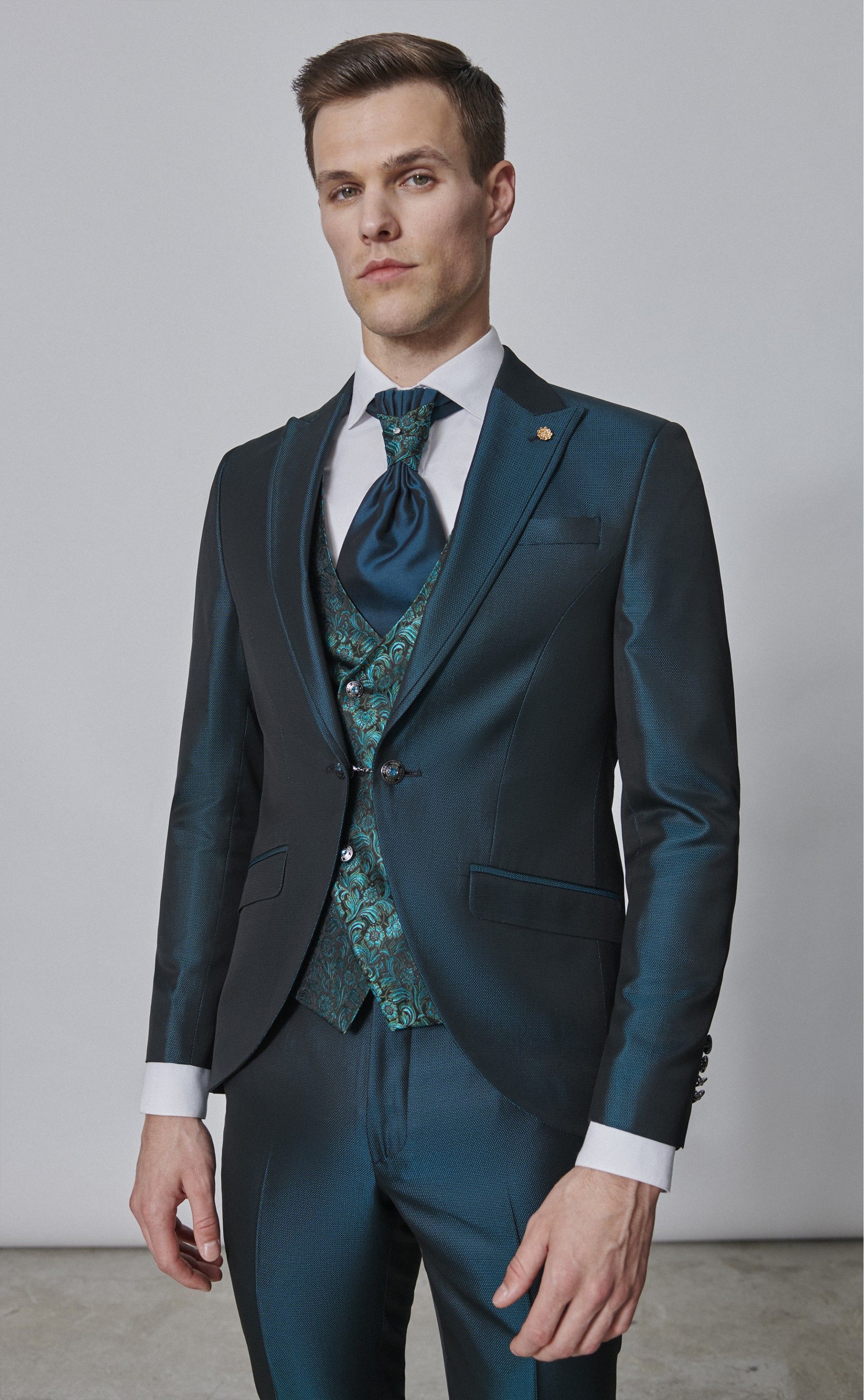 Un uomo in giacca e cravatta è in piedi davanti a un muro bianco.