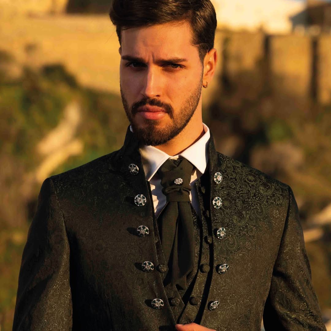 Un uomo con la barba indossa un abito nero e una cravatta