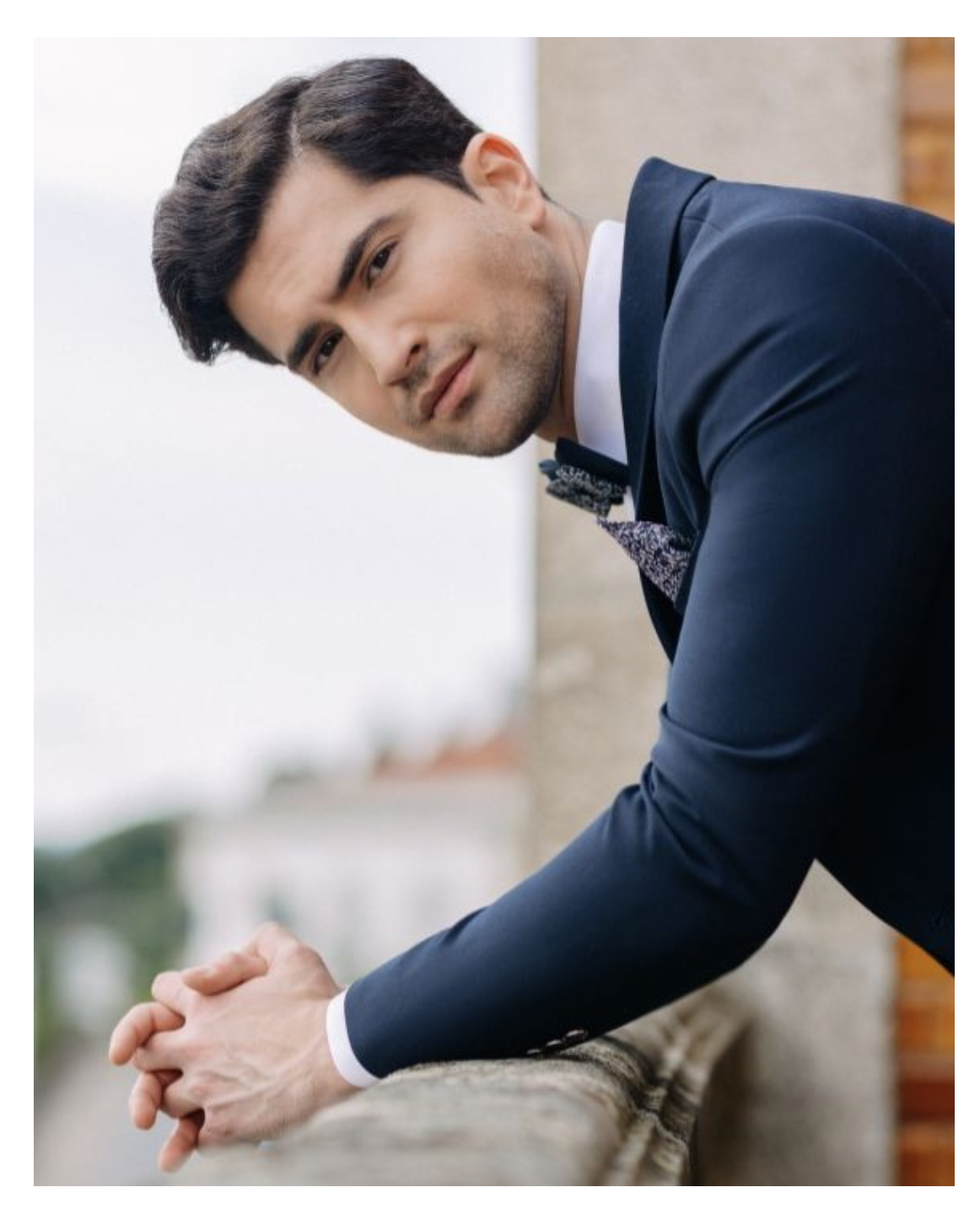 Un uomo in giacca e cravatta appoggiato a una ringhiera