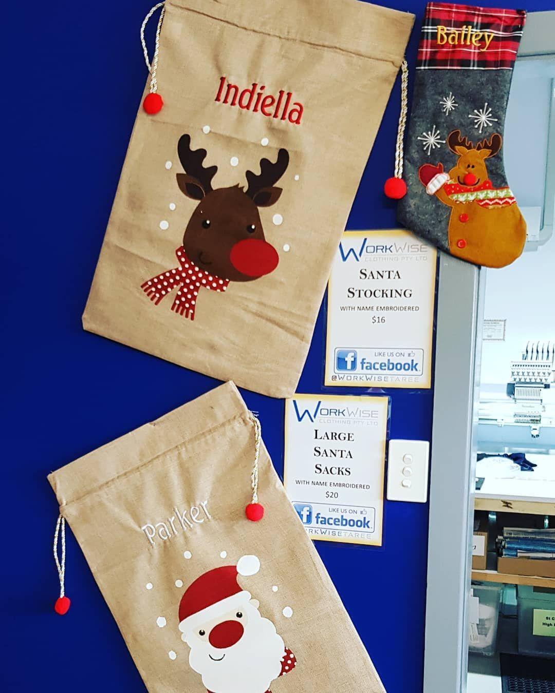 Two Personalized Christmas Gift Bags and a Stocking on a Blue Wall — Workwise Clothing Forster in Forster, NSW