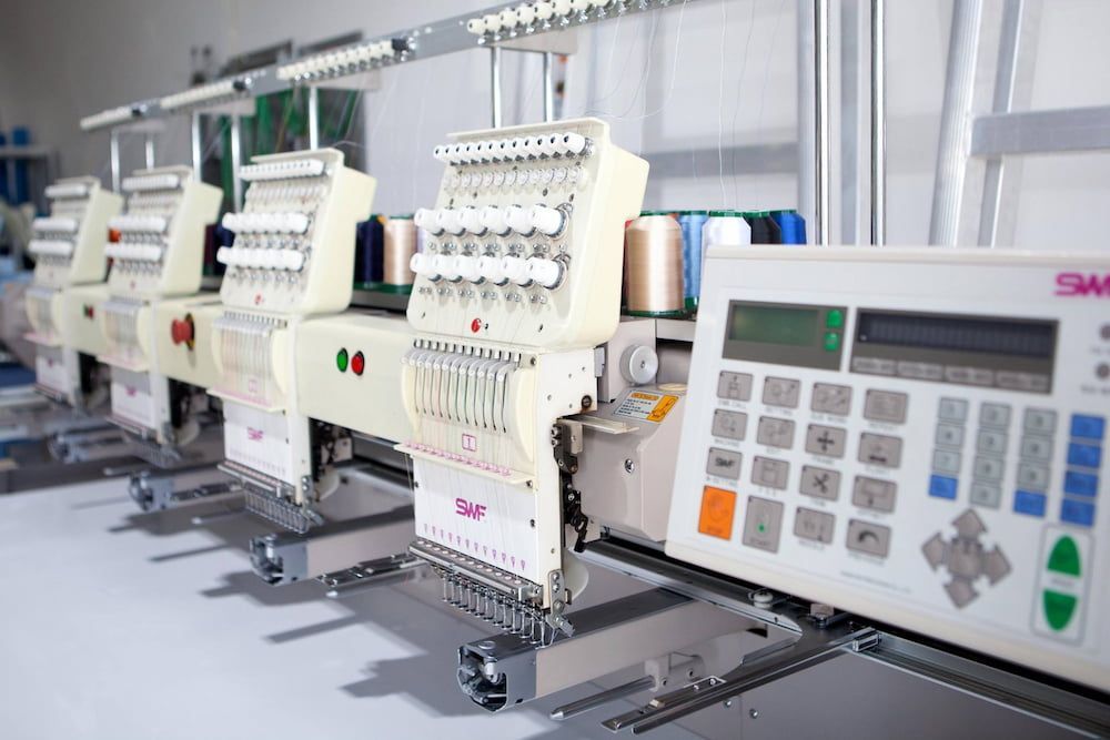 Row of Industrial Embroidery Machines With Spools of Thread, in a Workshop — Workwise Clothing Forster in Forster, NSW