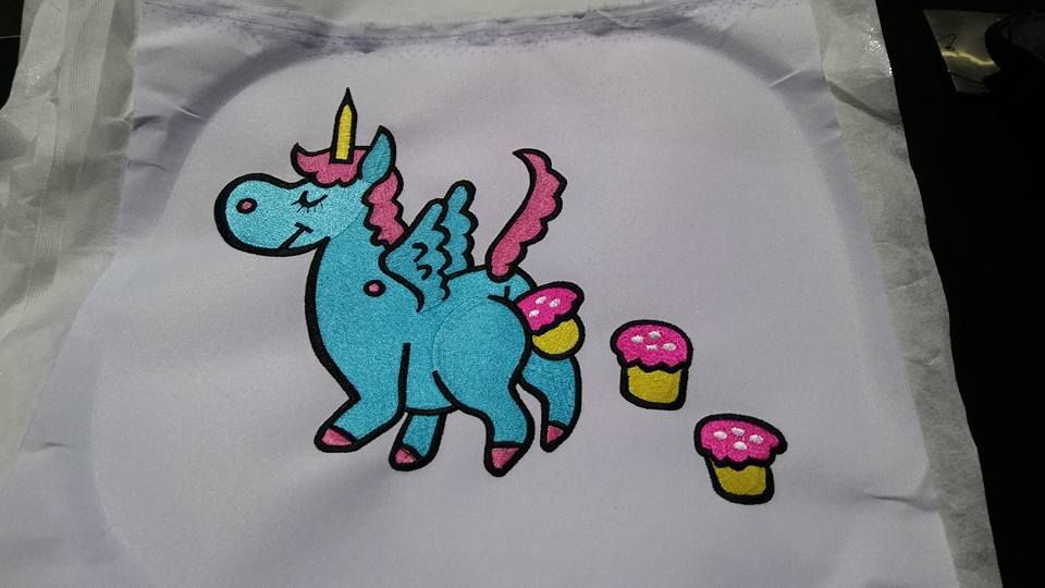 Blue Unicorn Embroidery With Pink Accents and Cupcakes on White Fabric — Workwise Clothing Forster in Forster, NSW