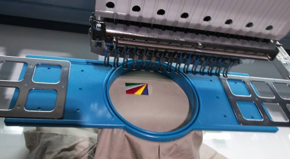 Embroidery Machine Stitching a Multi-colored Logo Onto Tan Fabric — Workwise Clothing Forster in Forster, NSW