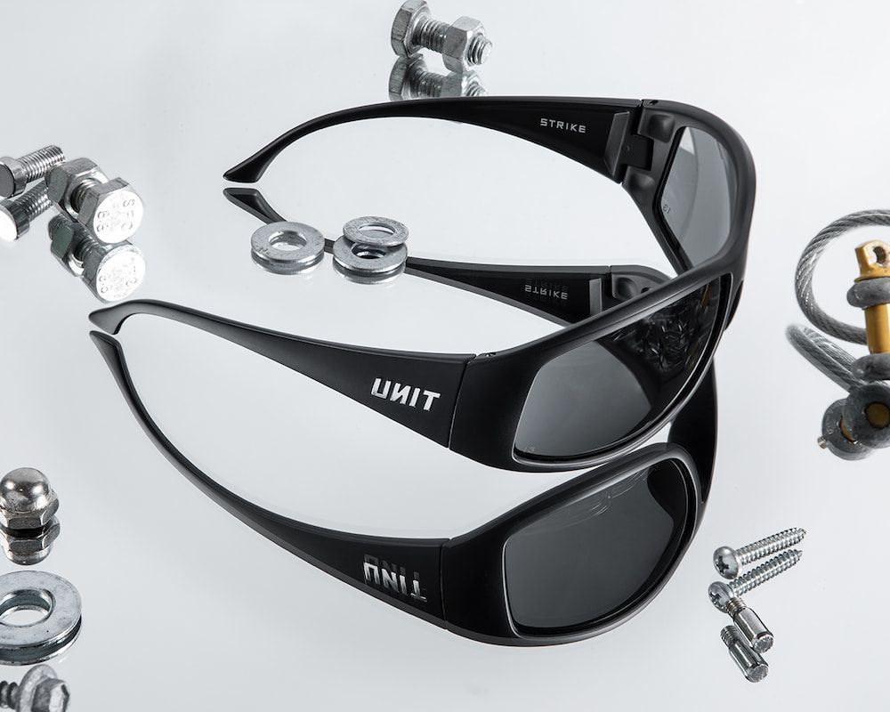 Two Black Unit Sunglasses Rest on a Reflective Surface — Workwise Clothing Forster in Forster, NSW