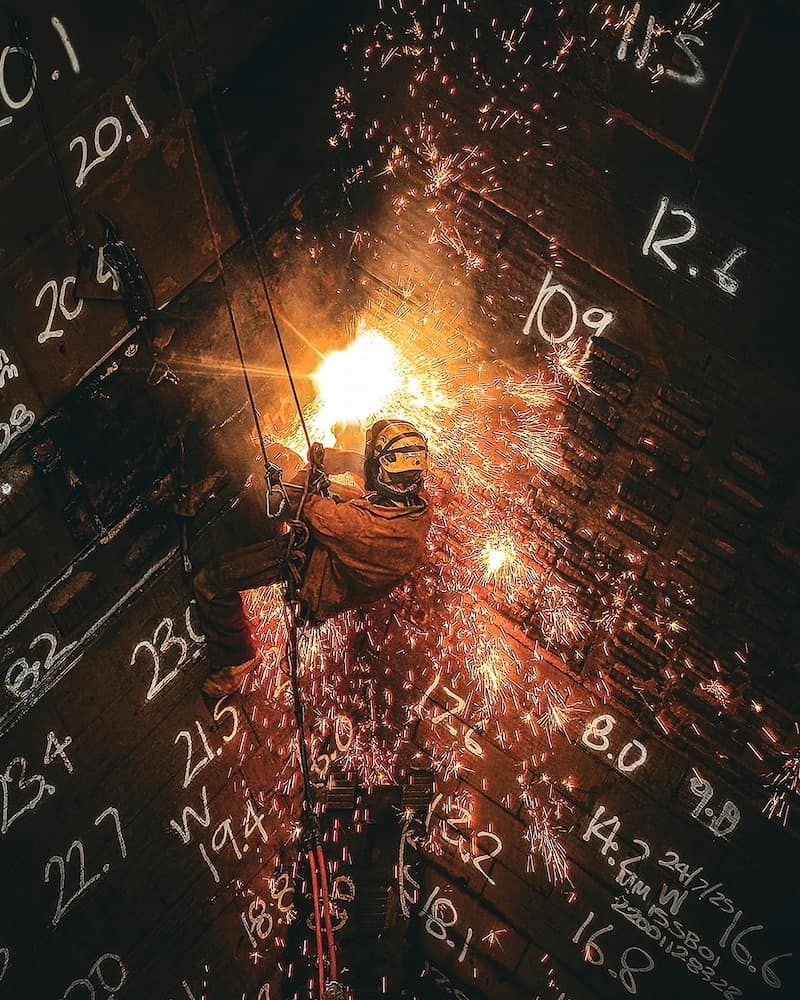 Welder Inside a Dark Structure, Sparks Flying, Torch Lit — Workwise Clothing Forster in Forster, NSW