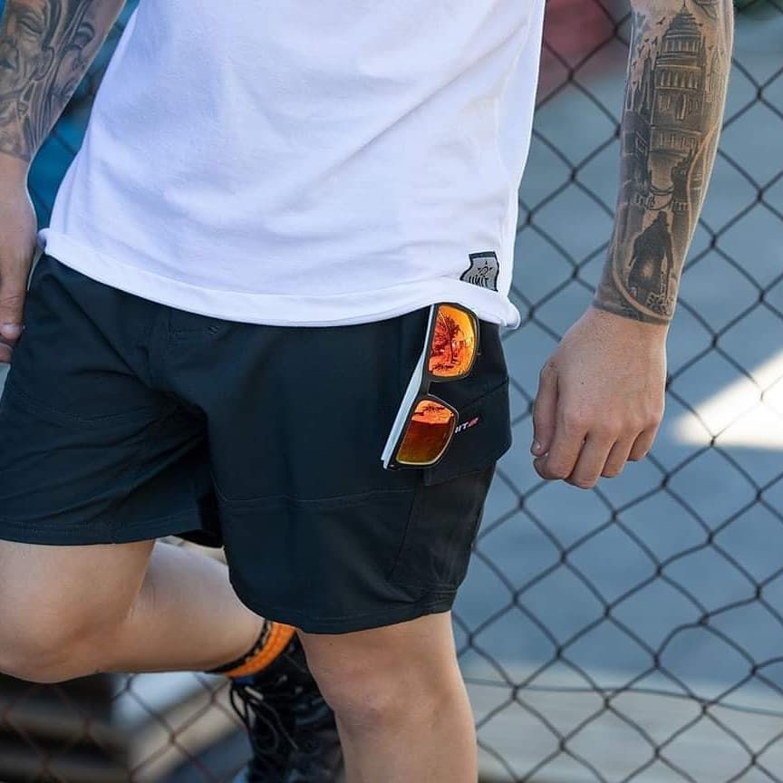 Man in White Shirt and Black Shorts Leaning Against a Fence — Workwise Clothing Forster in Forster, NSW