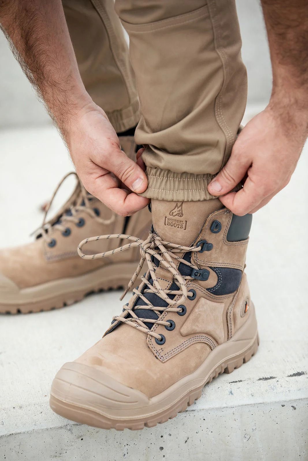 Man adjusting the elastic cuff of work pants over a work boot — Workwise Clothing Forster in Forster, NSW
