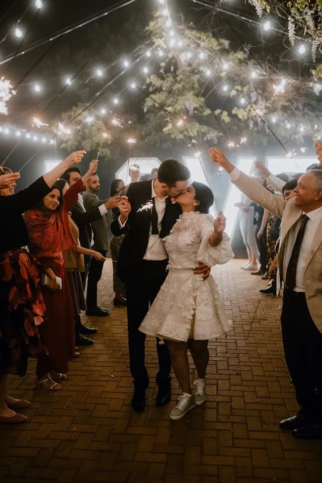 A bride and groom kissing under a canopy of sparklers at their wedding reception.