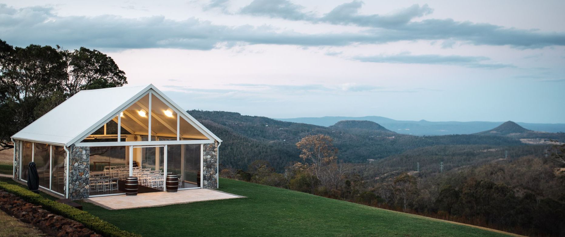 A large white tent is sitting on top of a lush green hillside.