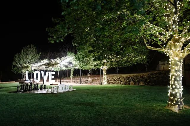 A large love sign is sitting under a tree in a park at night.