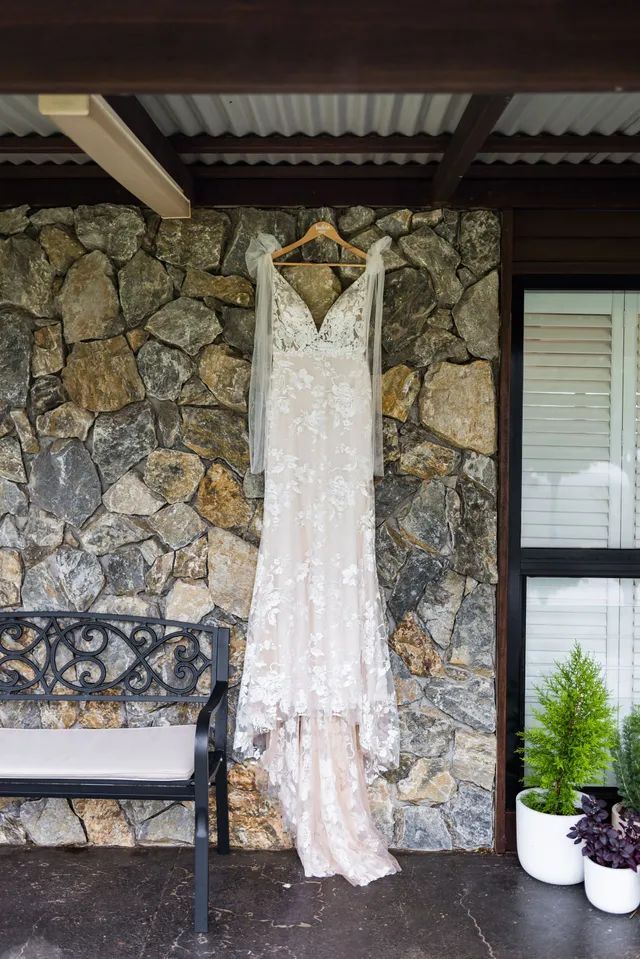 A wedding dress is hanging on a hanger on a porch.