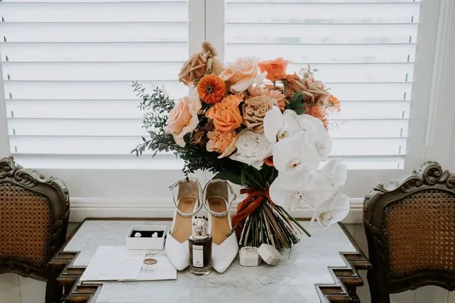 A bouquet of flowers and a pair of shoes are on a table.