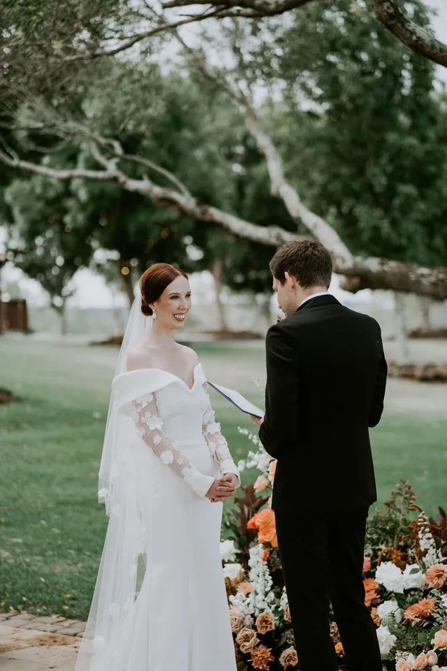 A bride and groom are holding hands during their wedding ceremony.