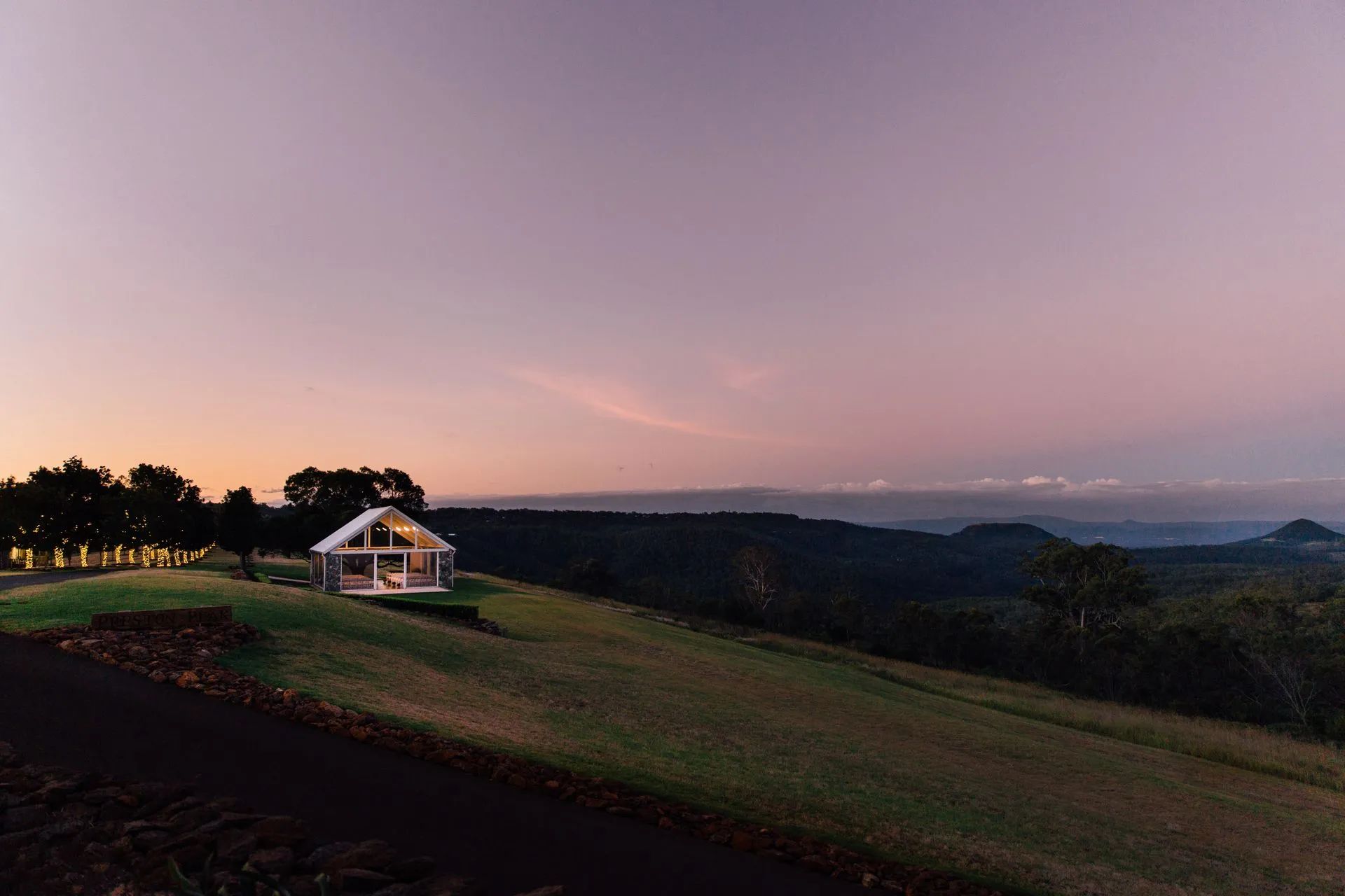 A small white house is sitting on top of a hill at sunset.