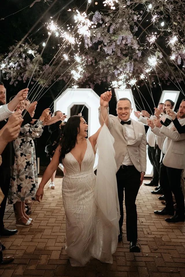 A bride and groom are walking through a tunnel of sparklers.
