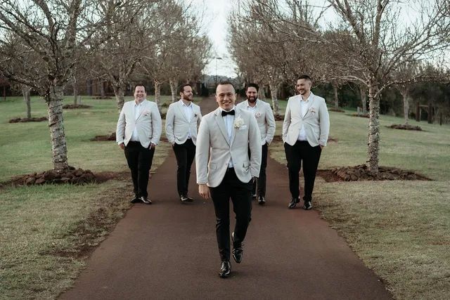 A groom and his groomsmen are walking down a path.