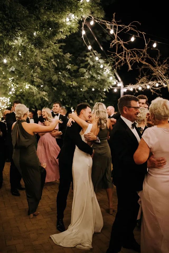 A bride and groom are dancing with their wedding party at a wedding reception.