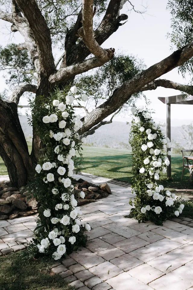 A tree decorated with white flowers and greenery for a wedding ceremony.
