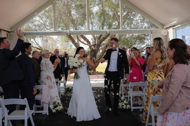 A bride and groom are walking down the aisle at their wedding.
