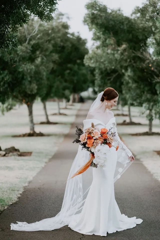 A bride in a wedding dress is holding a bouquet of flowers.