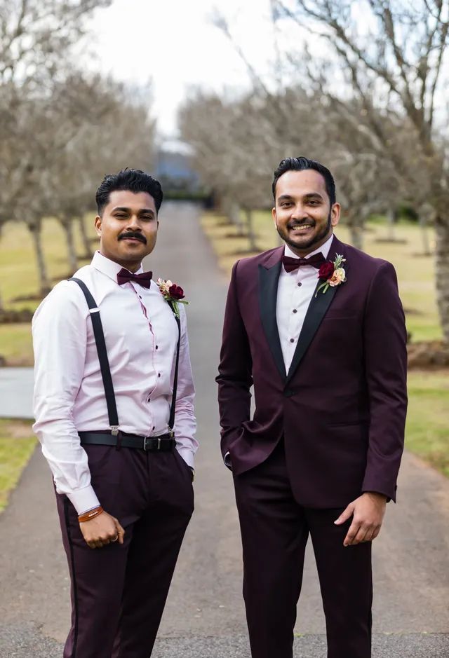 Two men in suits and bow ties are standing next to each other on a road.