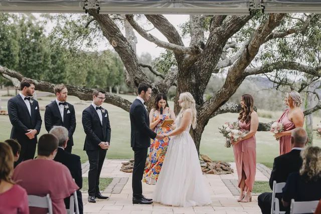 A bride and groom are holding hands during their wedding ceremony under a canopy.