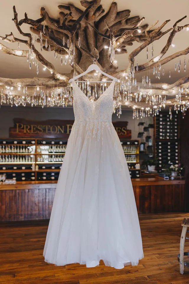 A wedding dress is hanging from a tree in a room.