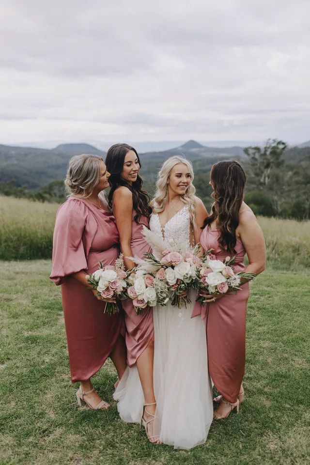 A bride and her bridesmaids are posing for a picture in a field.