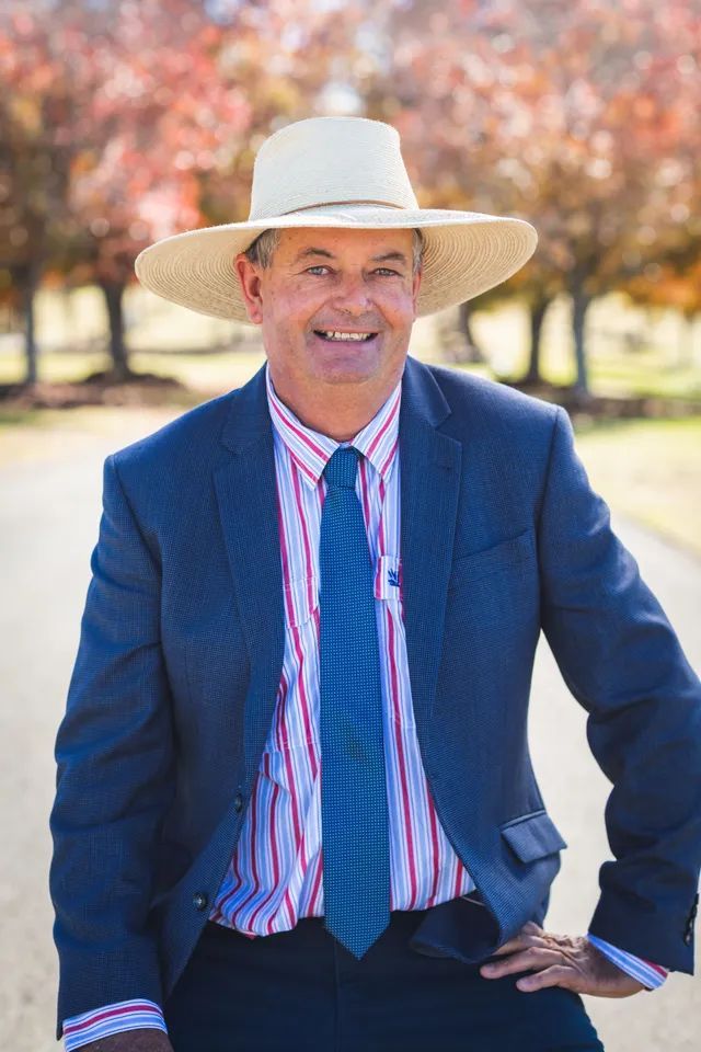 A man in a suit and hat is standing with his hands on his hips.