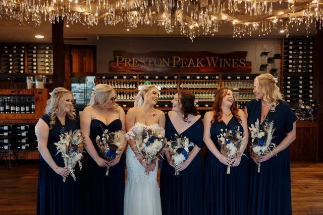 A bride and her bridesmaids are posing for a picture in a wine store.